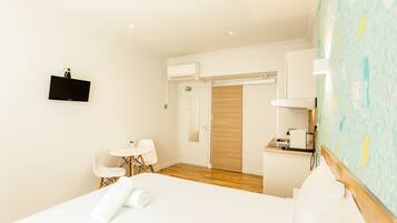 Habitación de hotel con cama, escritorio, silla, mesita y baño con espejo y lavamanos.