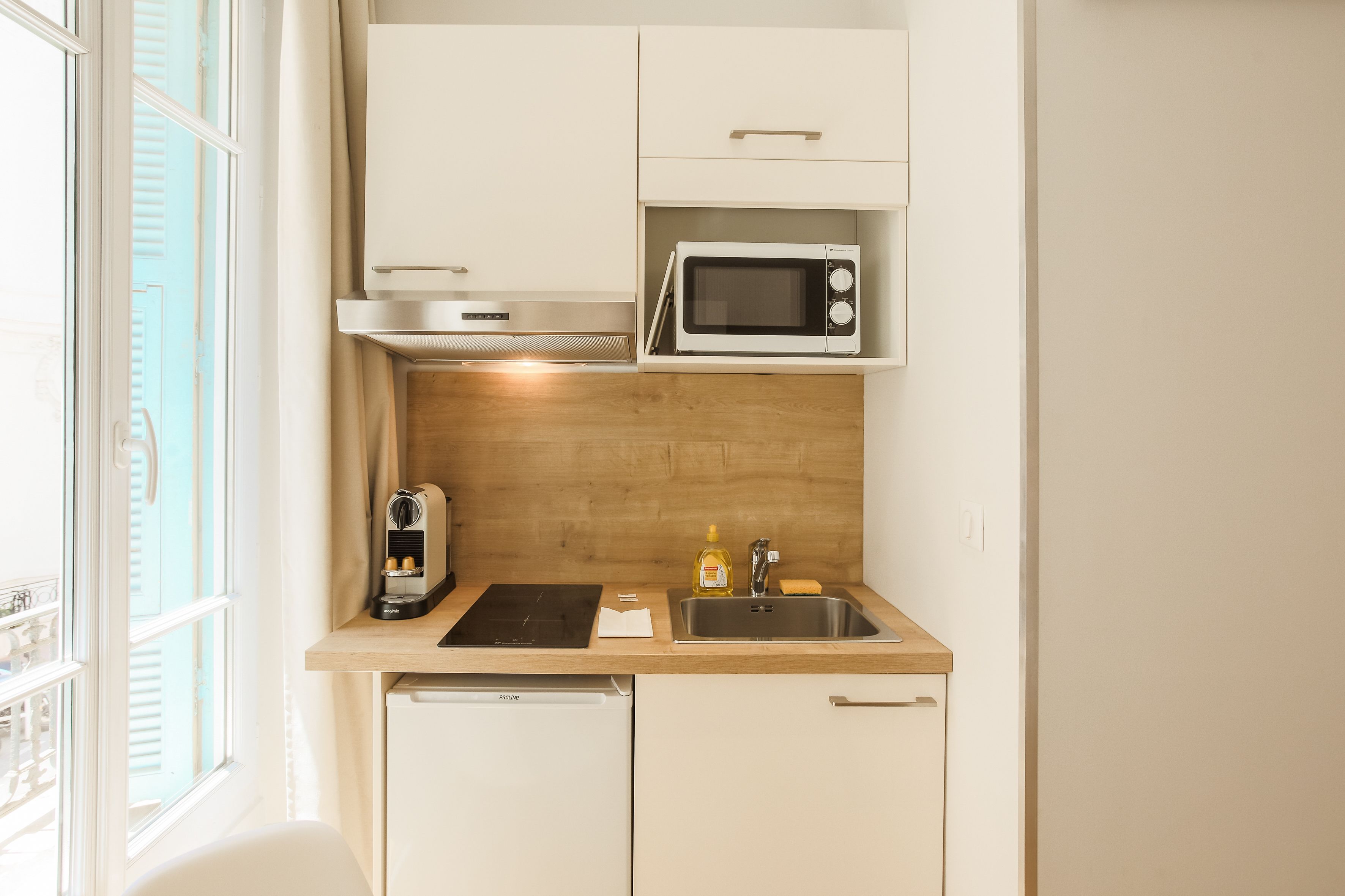 A compact kitchen with a microwave, sink, and a compact dishwasher.
