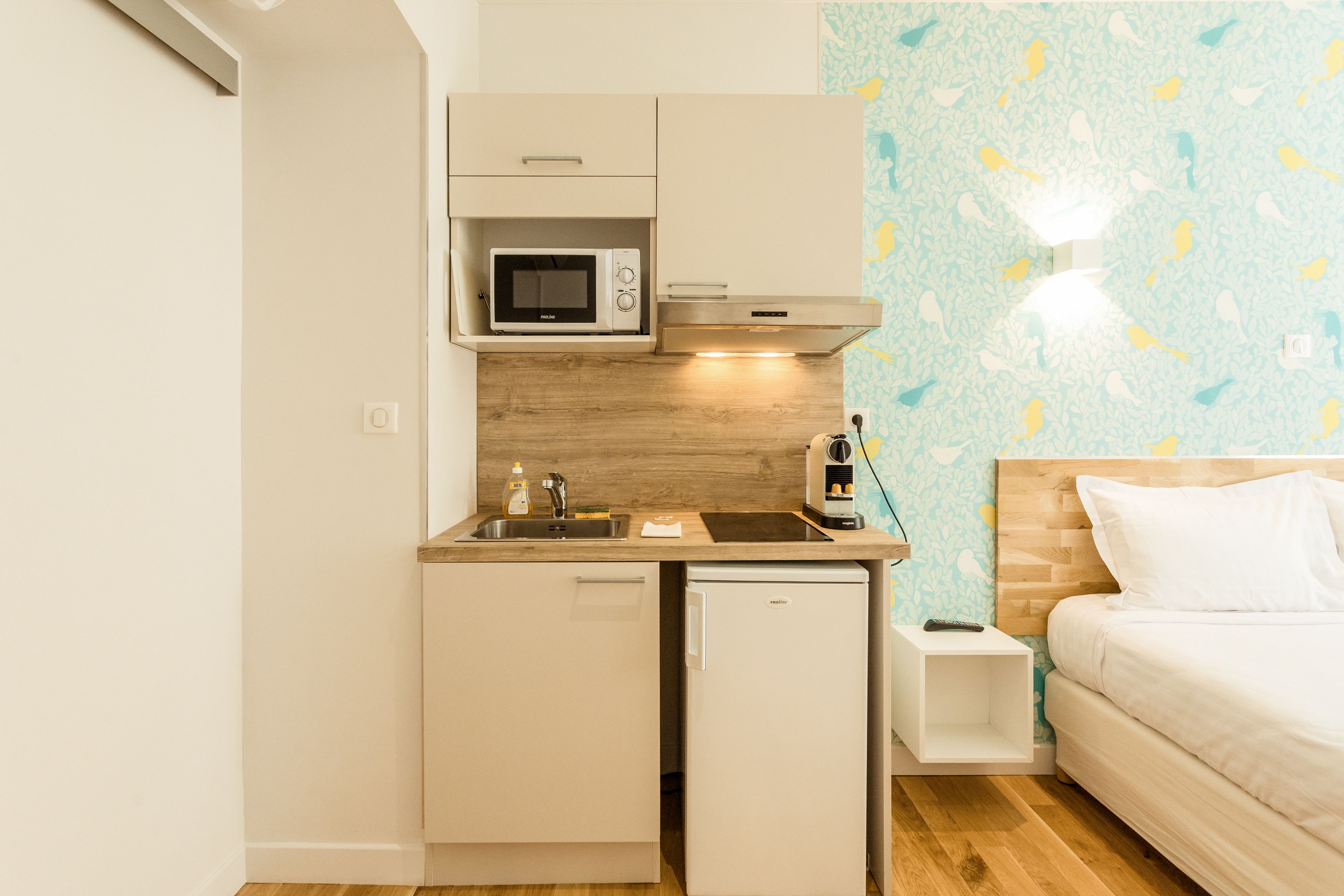 A compact kitchenette with a microwave, sink, and a small refrigerator.