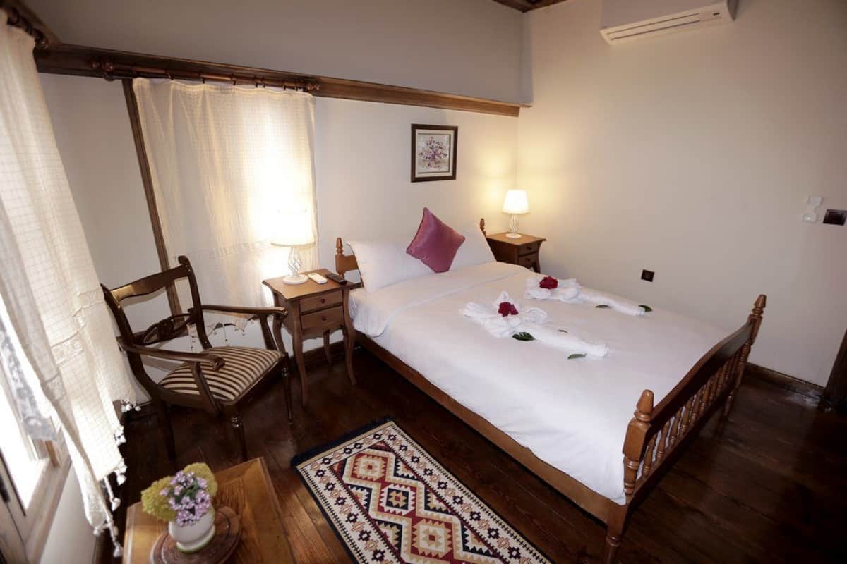 Une chambre à coucher bien rangée, avec un lit en bois, une chaise, une table de chevet et un tapis à motifs.