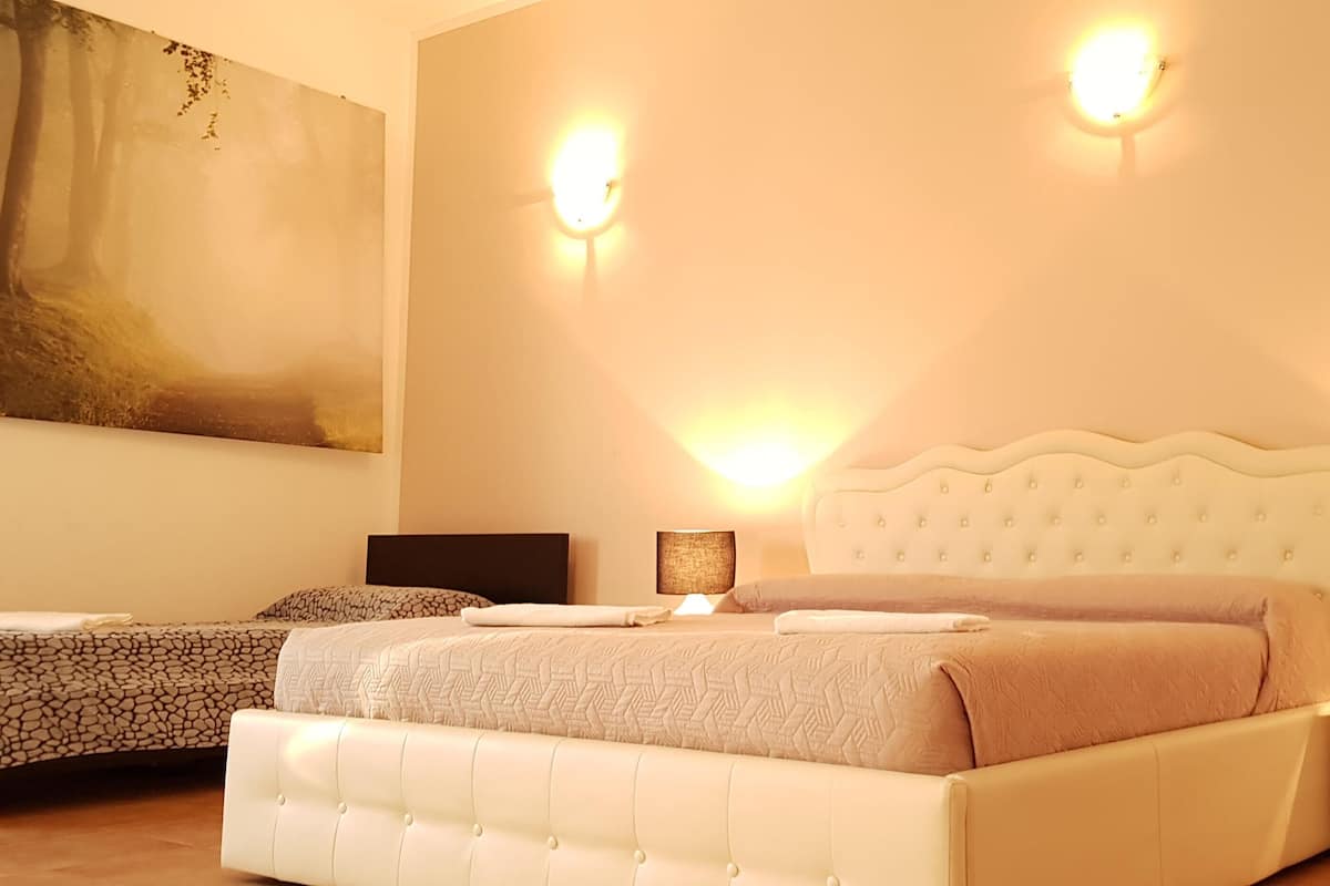 A bedroom with a large bed, two bedside tables, and a wall-mounted lamp.