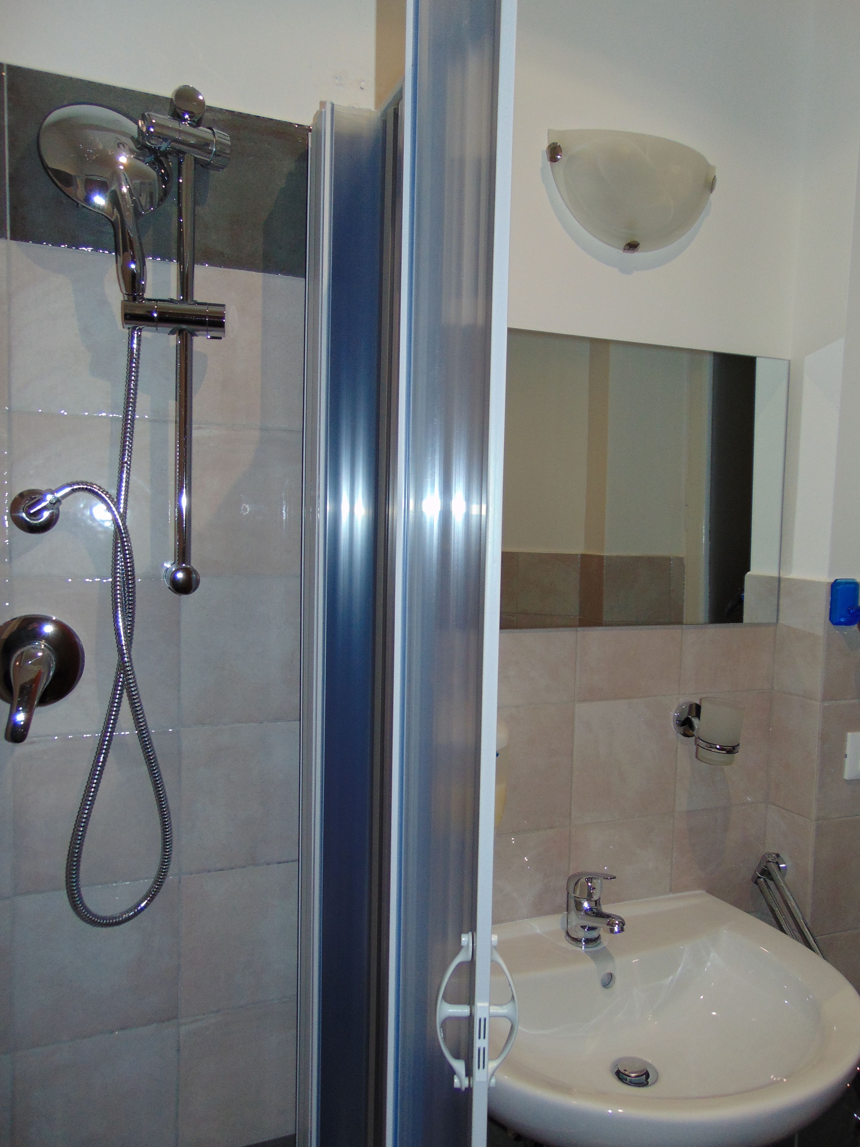 Un baño con cabina de ducha de vidrio, lavamanos y espejo.