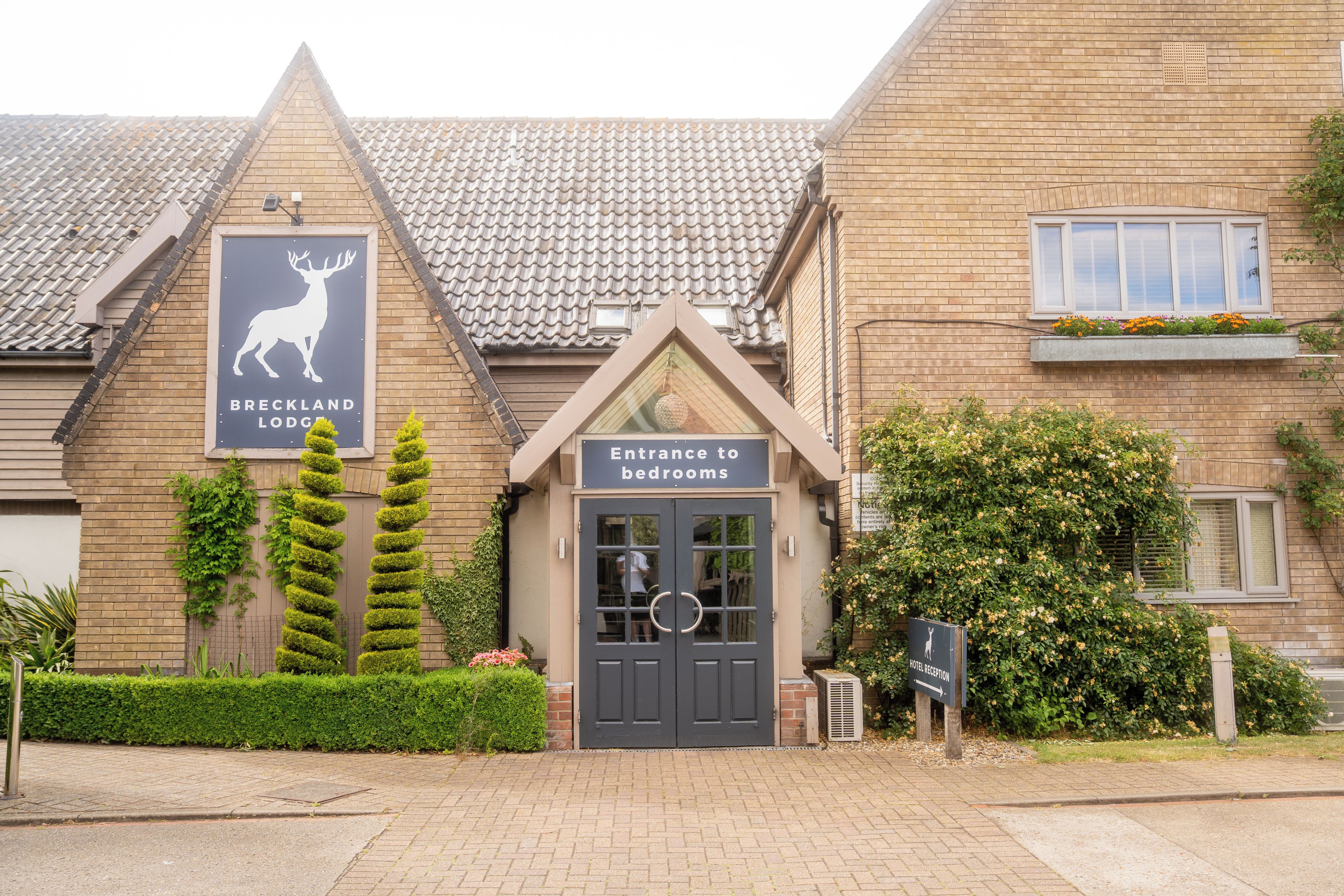 A building with a sign for 'Breckland Lodge' and an entrance to bedrooms.