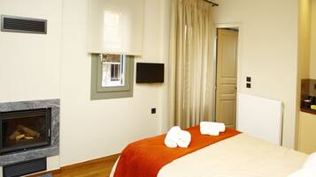 A hotel room with a fireplace, a bed with an orange blanket, and a window with curtains.