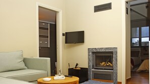 A living room with a sofa, a coffee table, a fireplace, and a television. - Kazas Luxury Apartments (Gortynia)