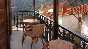 A balcony with wicker chairs and a table, overlooking a mountainous landscape. - Kazas Luxury Apartments (Gortynia)
