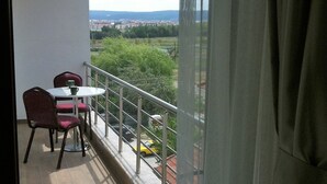 Ein Balkon mit Tisch und Stühlen, Blick auf eine Stadtlandschaft und einer Brüstung.