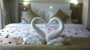Ein Hotelzimmer mit einem Bett, das mit einer Schwanen- und Enten-Handtuchgestaltung dekoriert ist, einem hölzernen Kopfteil und einer neutralen Farbgestaltung.