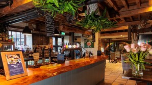 Eine Bar mit Holztresen, hängenden Pflanzen und einer Speisekarte.