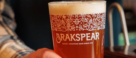 A hand holding a glass of beer with a label reading "BRAKSPEAR DOUBLE DROPPING BEER SINCE 1779".