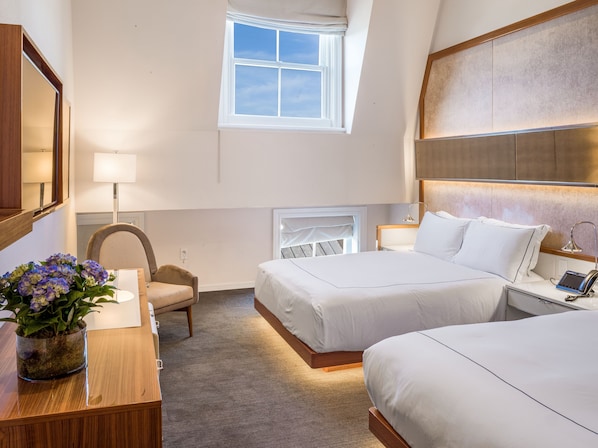 A hotel room with two beds, a desk, a chair, a bedside table, a lamp, and a window with a view of the sky. - 33 Hotel, New York City, Seaport (New York)