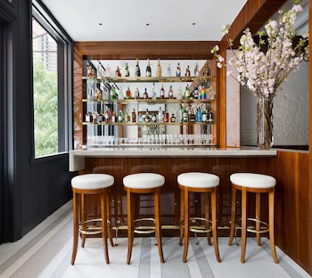 A hotel room with a large bed, a wooden wardrobe, a bedside table with a lamp, and a view of the city through a window. at 33 Hotel, New York City, Seaport