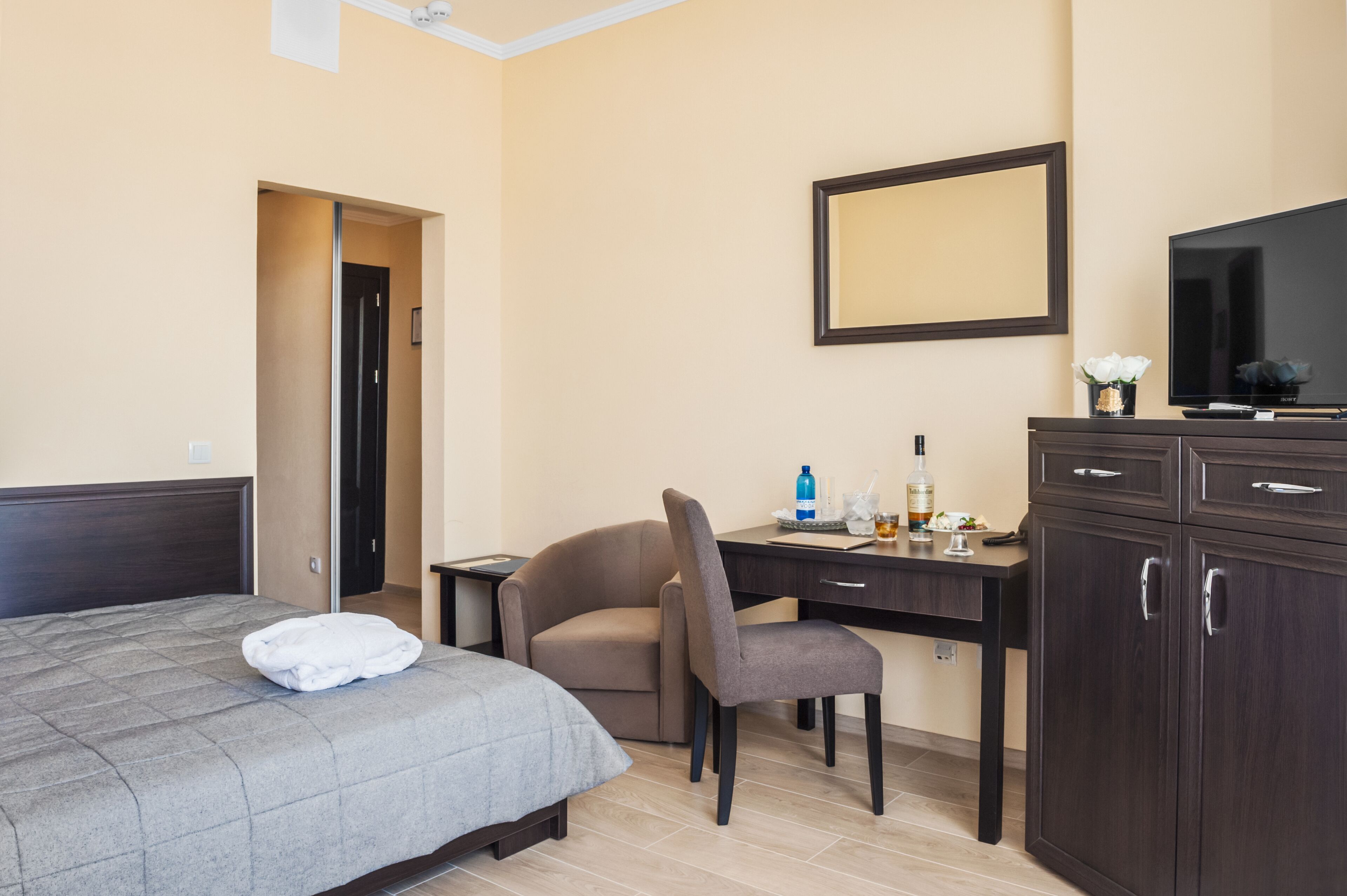 A hotel room with a bed, a desk, a chair, a TV, and a cabinet.