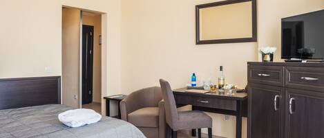 A hotel room with a bed, a desk, a chair, a TV, and a cabinet.