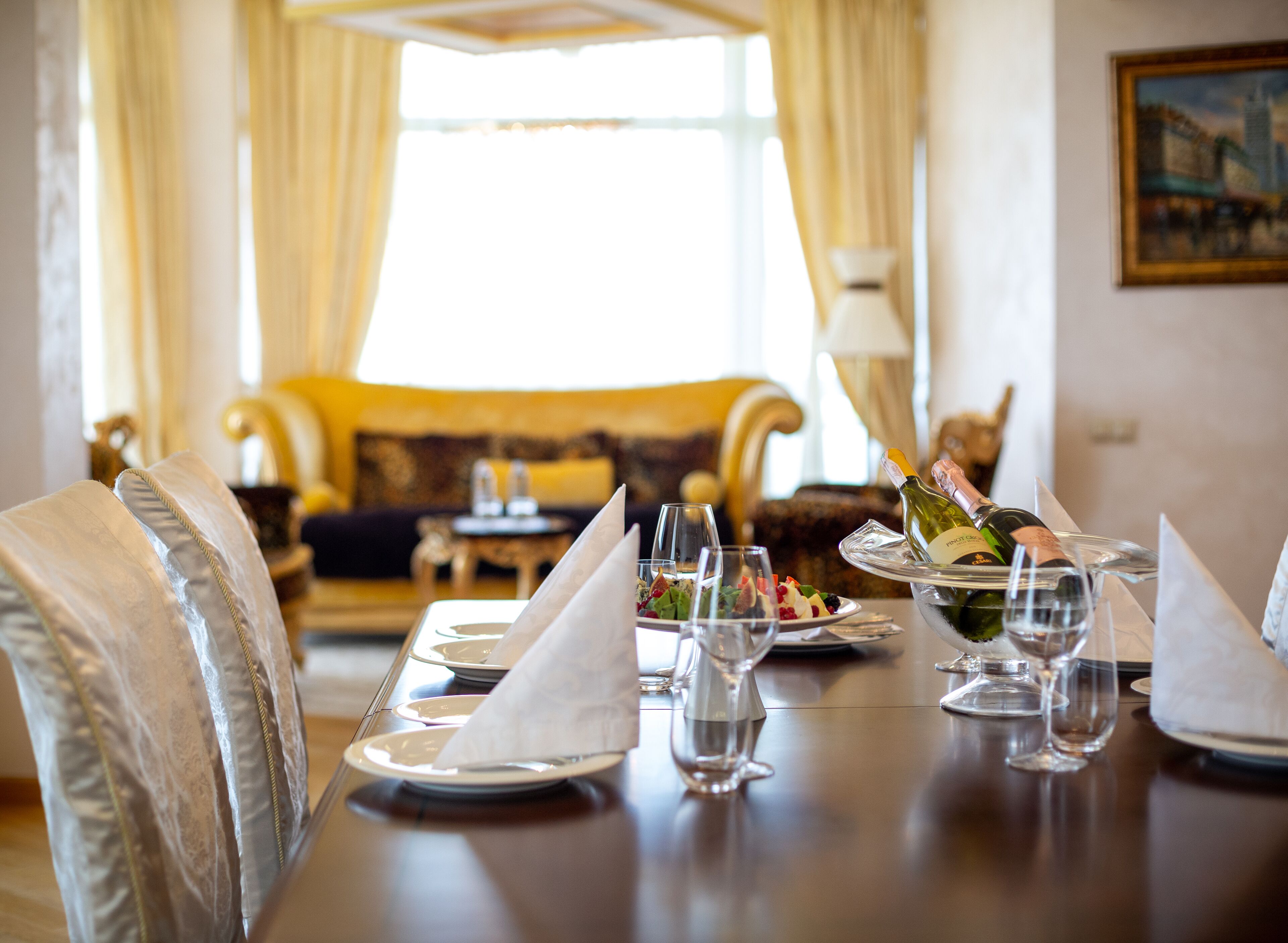 A dining table set with plates, glasses, and a bottle of champagne.