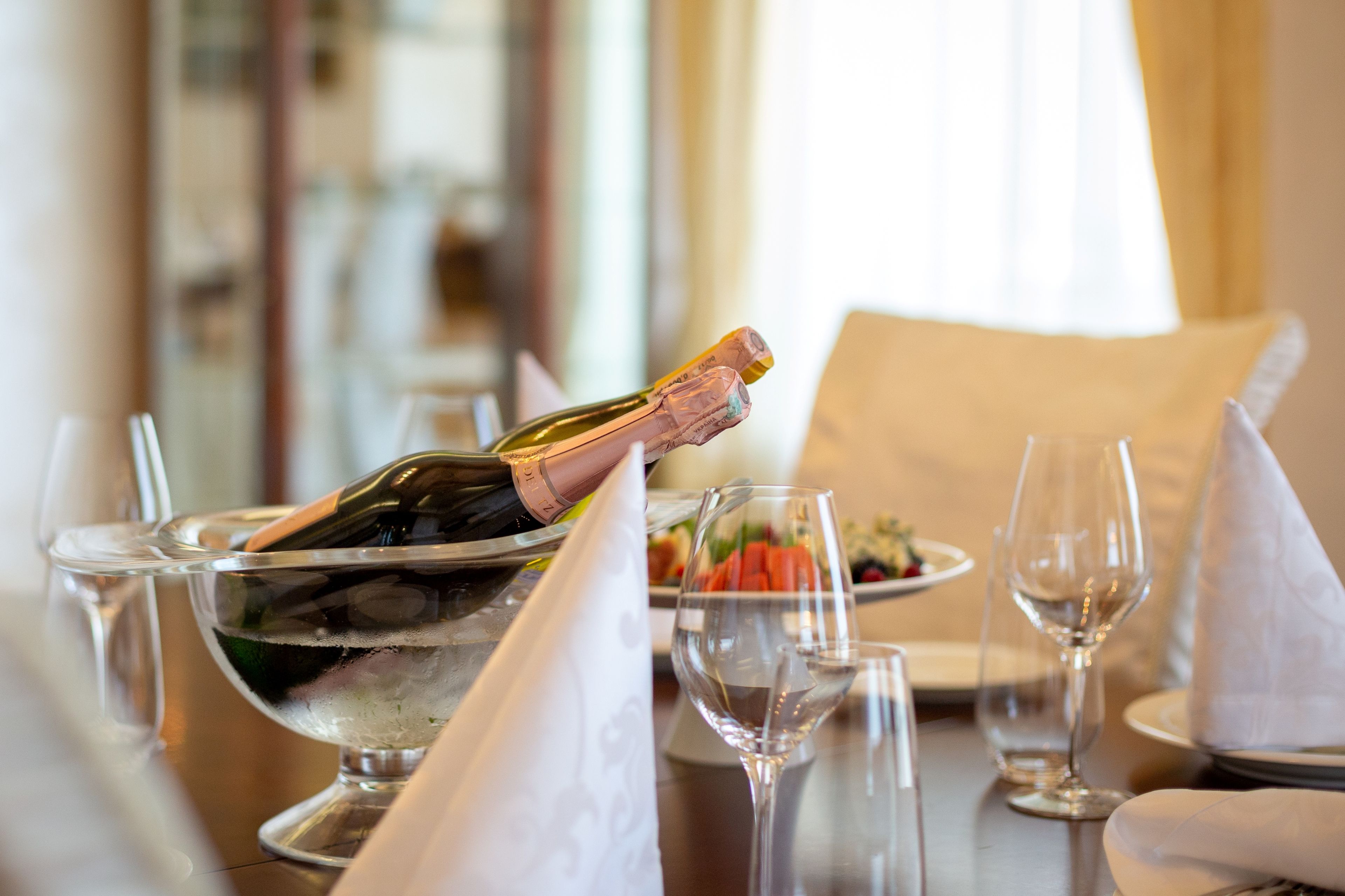 Een gedekte tafel voor diner, met een fles champagne, een schaal ijs en lege wijnglazen.