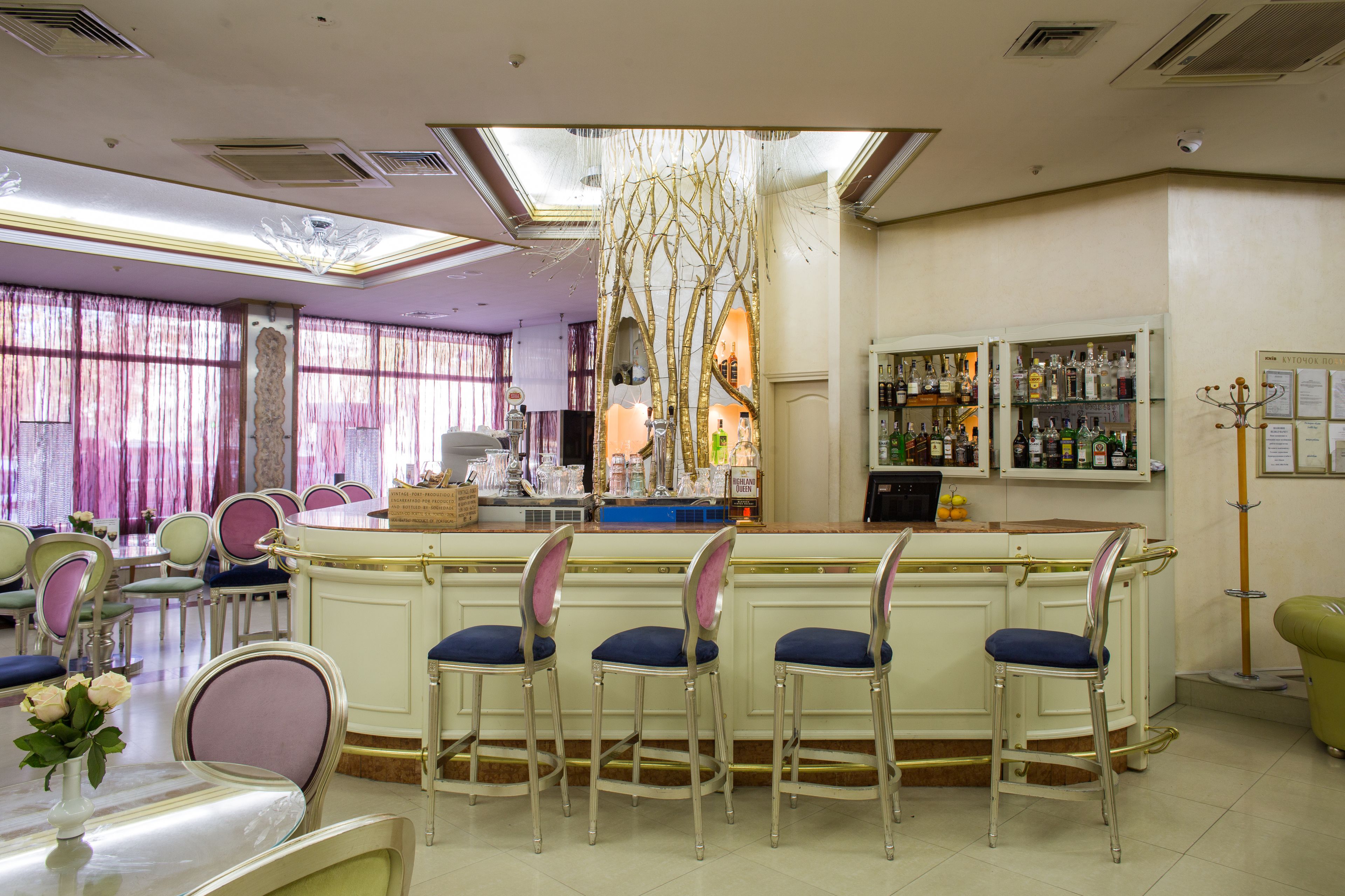 A bar area with a counter, bar stools, and a display of bottles.