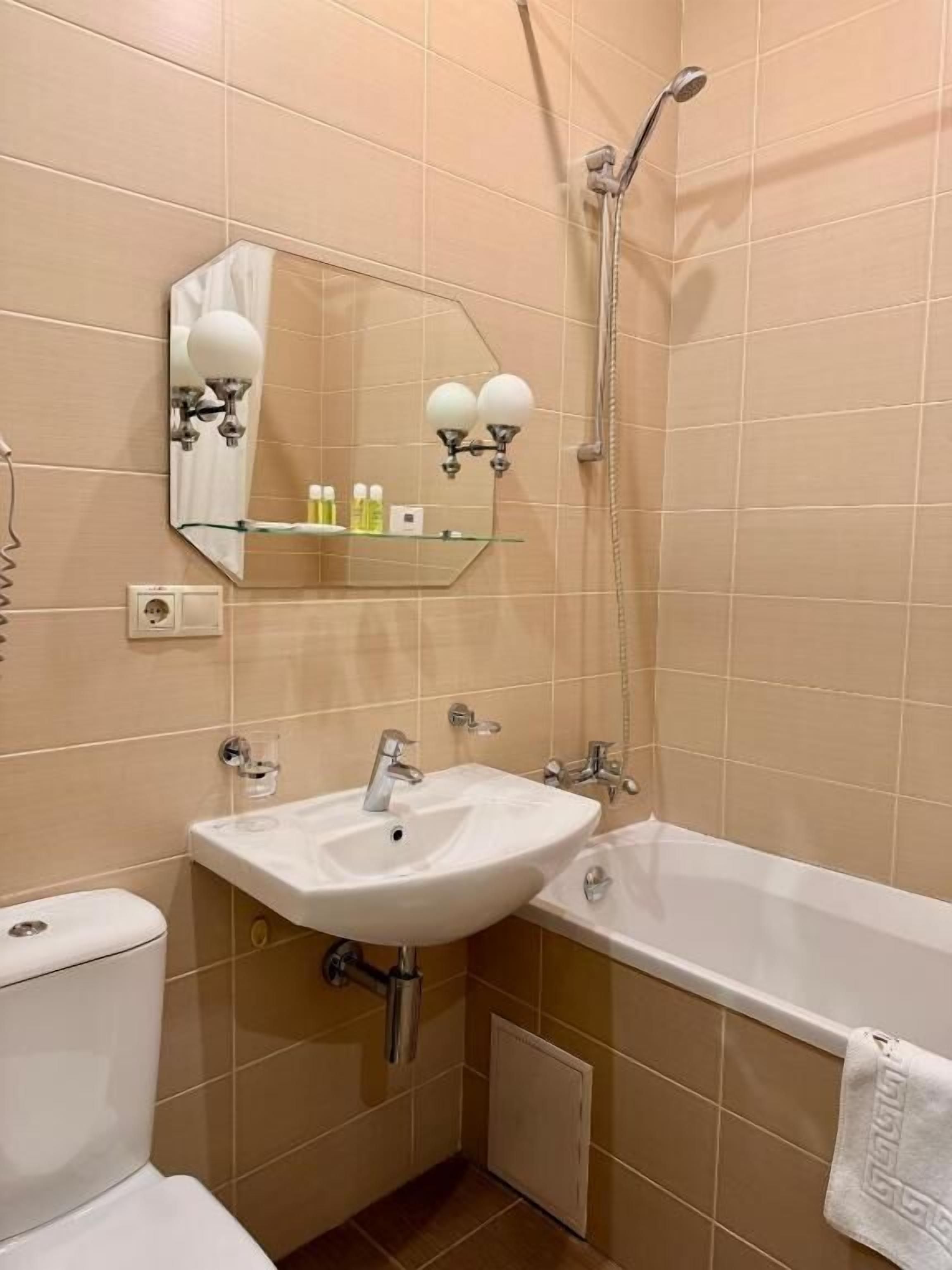 Een badkamer met een witte wastafel, een spiegel, een douche en een toilet.