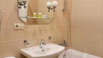 Un baño con un lavamanos blanco, un espejo, una ducha e inodoro.