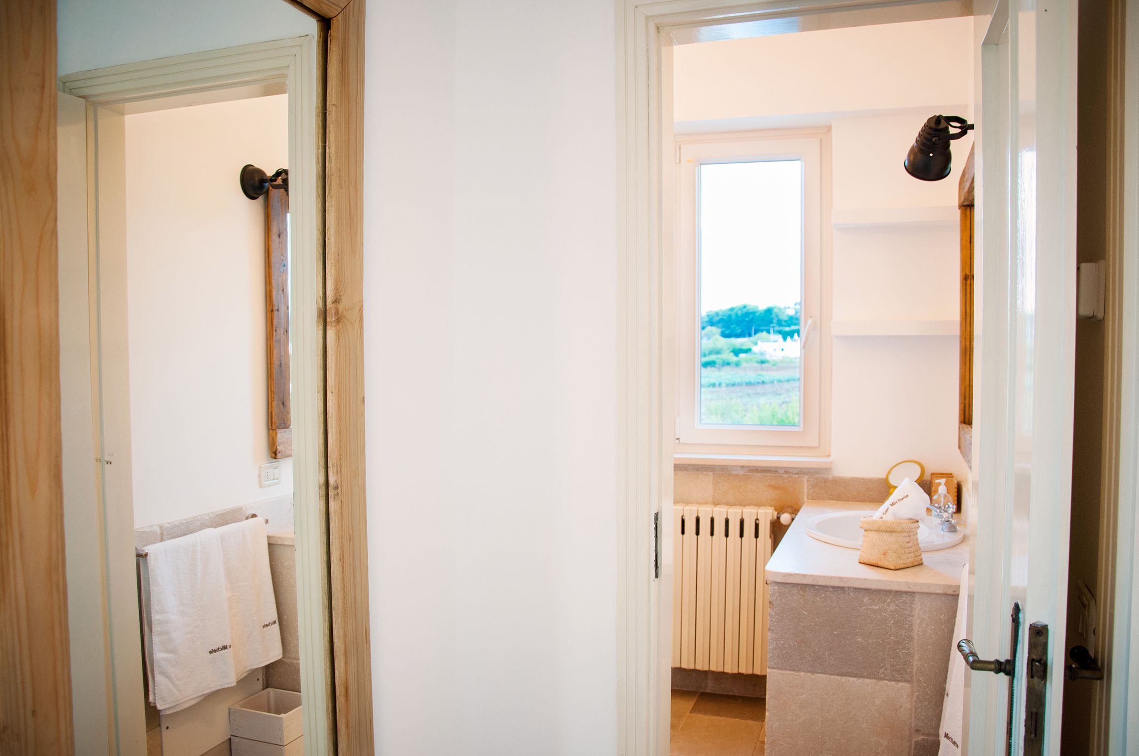 A bathroom with a window, a radiator, a sink, and a towel rack.