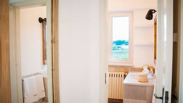 A bathroom with a window, a radiator, a sink, and a towel rack.