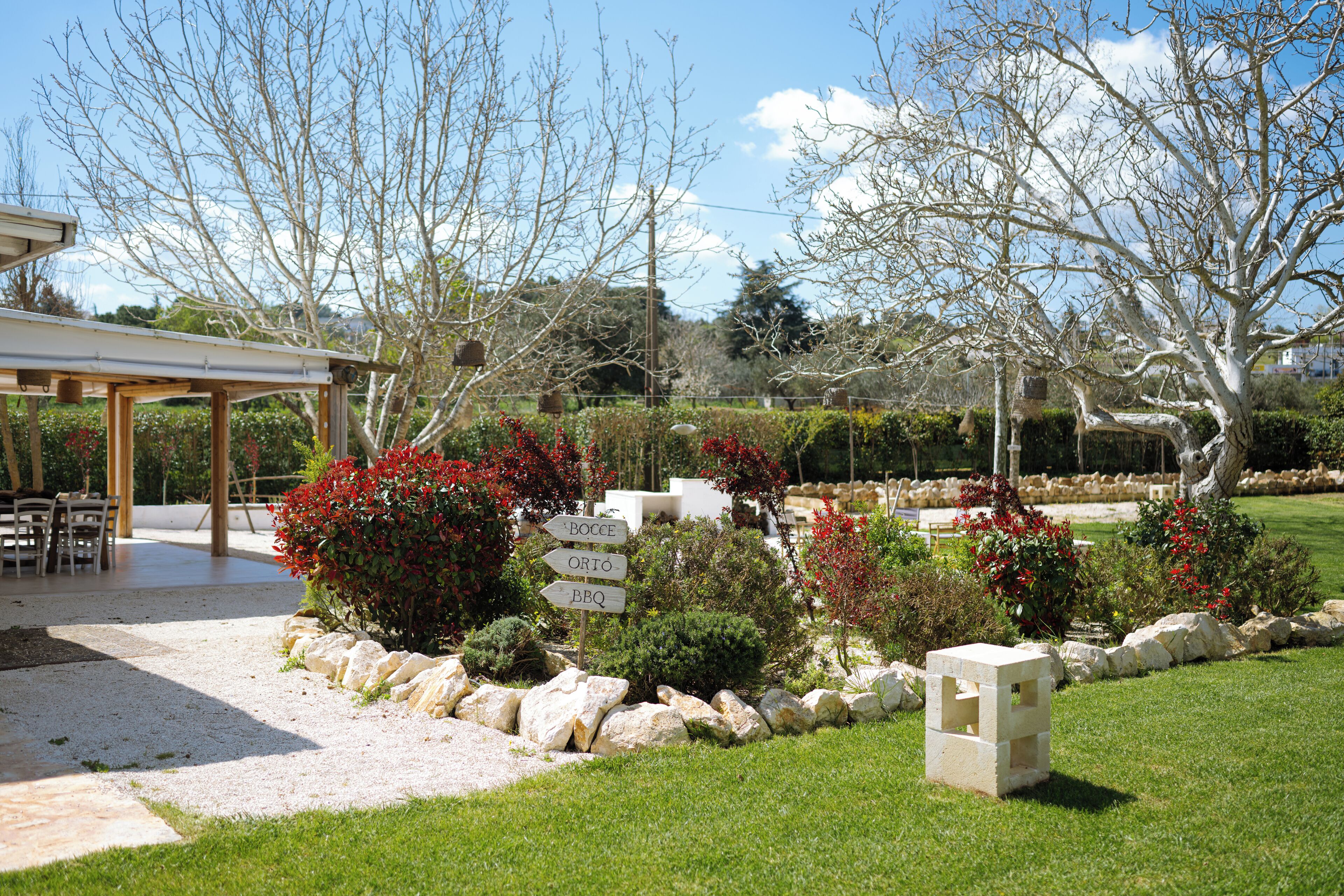 Un jardín con un pérgola, un sendero de piedra y señalización.