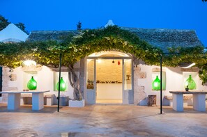 Un bâtiment doté d’une façade en pierre, d’un porche et de vases en verre vert placés sur des piédestaux.