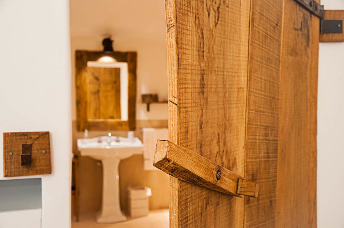 A wooden door in a bathroom with a mirror above a sink.