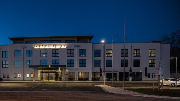 Et moderne hotel med en flad facade, mange vinduer og en godt oplyst indgang.
