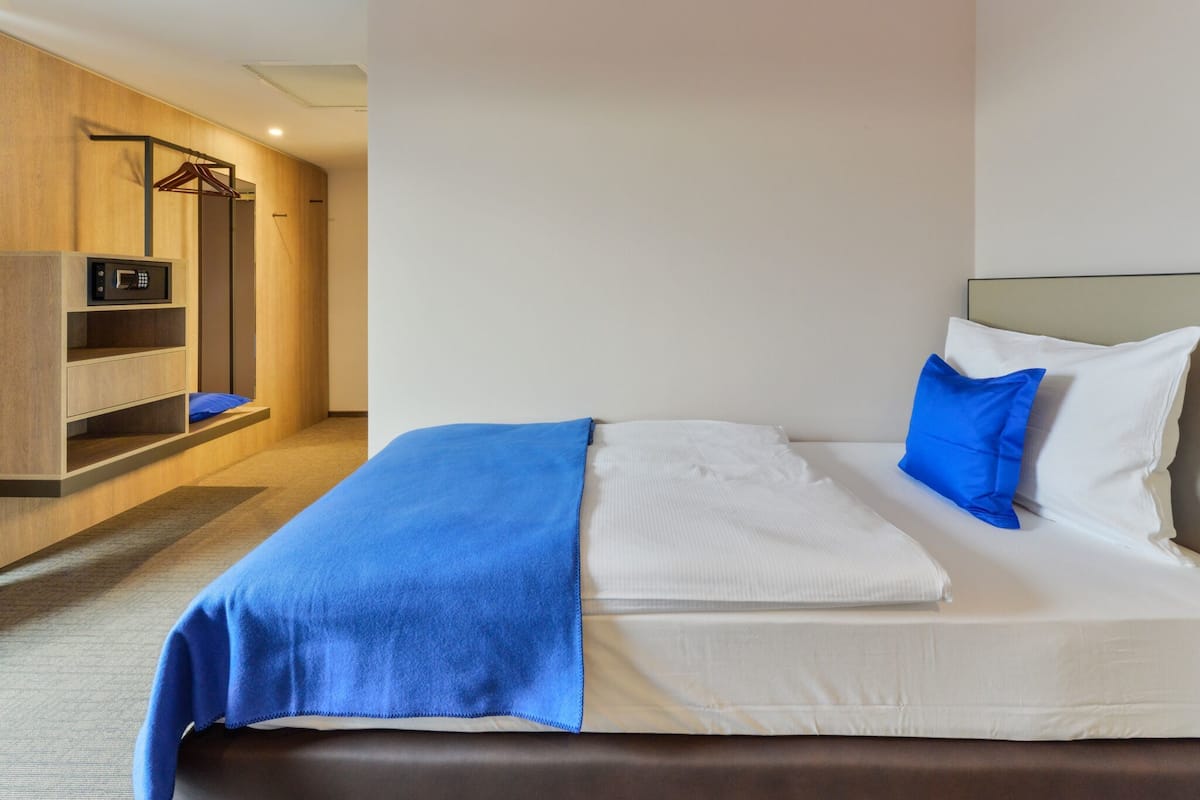 A hotel room with a bed, a wardrobe, a microwave, and a seating area.