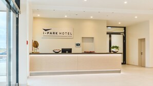 En moderne receptionsdisk på i-Park Hotel med et minimalistisk design, et digitalt ur og en potteplante.