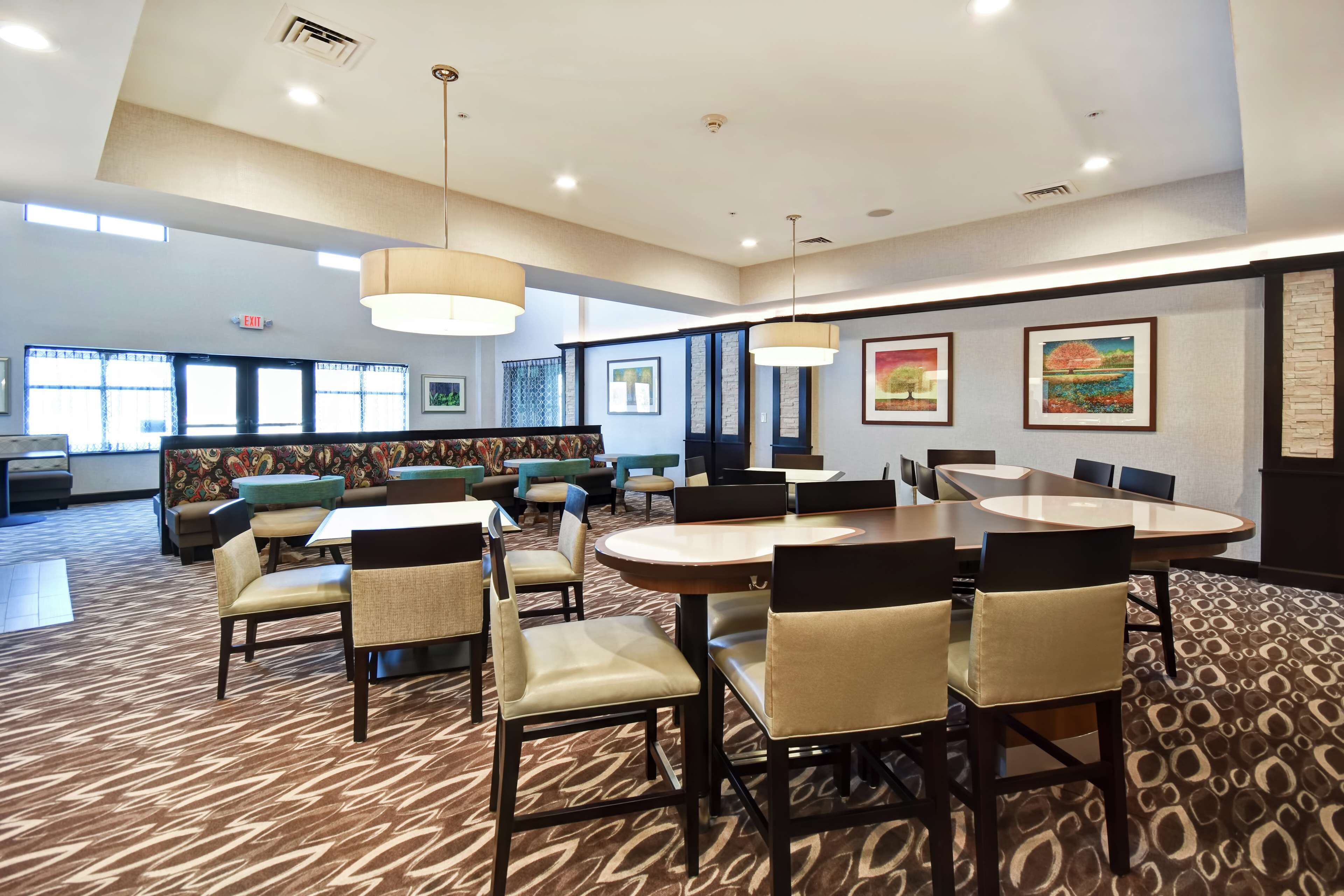 A conference room with a large table and chairs, a patterned carpet, and artwork on the walls.