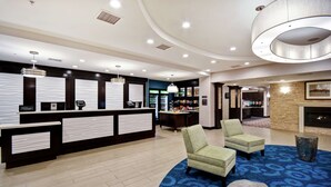 Un hall de hotel con una recepción, una zona de estar y una chimenea.