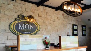 A reception desk with a sign reading "MON Boutique Hotel Constanza" and a wooden wall with a brick pattern. - MON Hotel Boutique (Constanza)