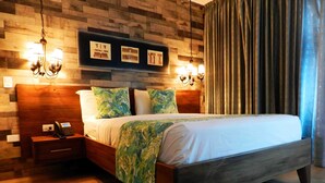 A bedroom with a wooden headboard, a bed with a green leaf-patterned blanket, two wall-mounted lamps, and a telephone on a bedside table. - MON Hotel Boutique (Constanza)