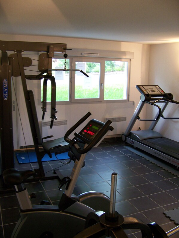 A home gym with a treadmill, elliptical, and weight machine. - City Résidence Marcy l'Etoile (Marcy-l'Etoile)
