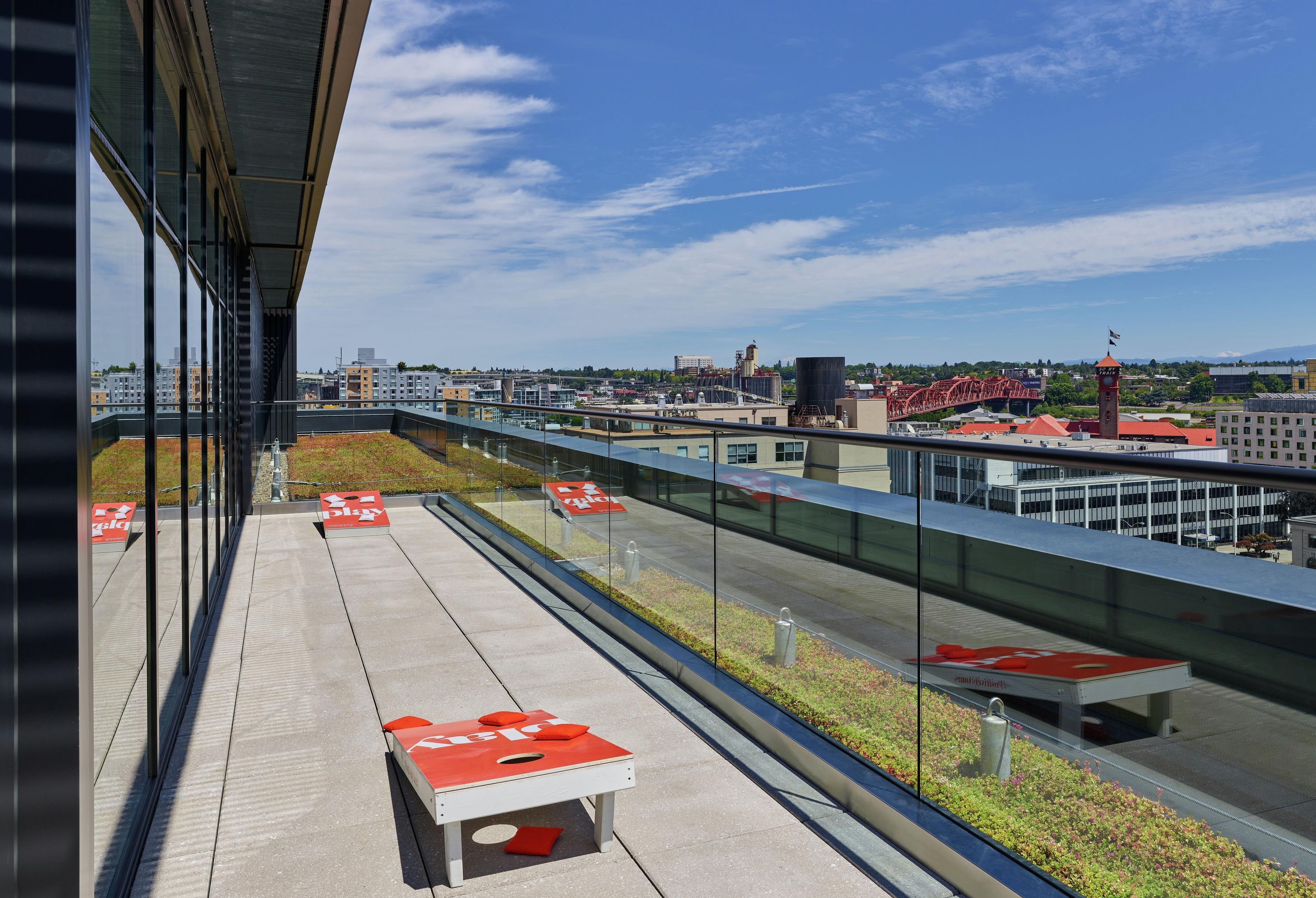 A modern building with a glass facade overlooking a cityscape, including a bridge and industrial structures.