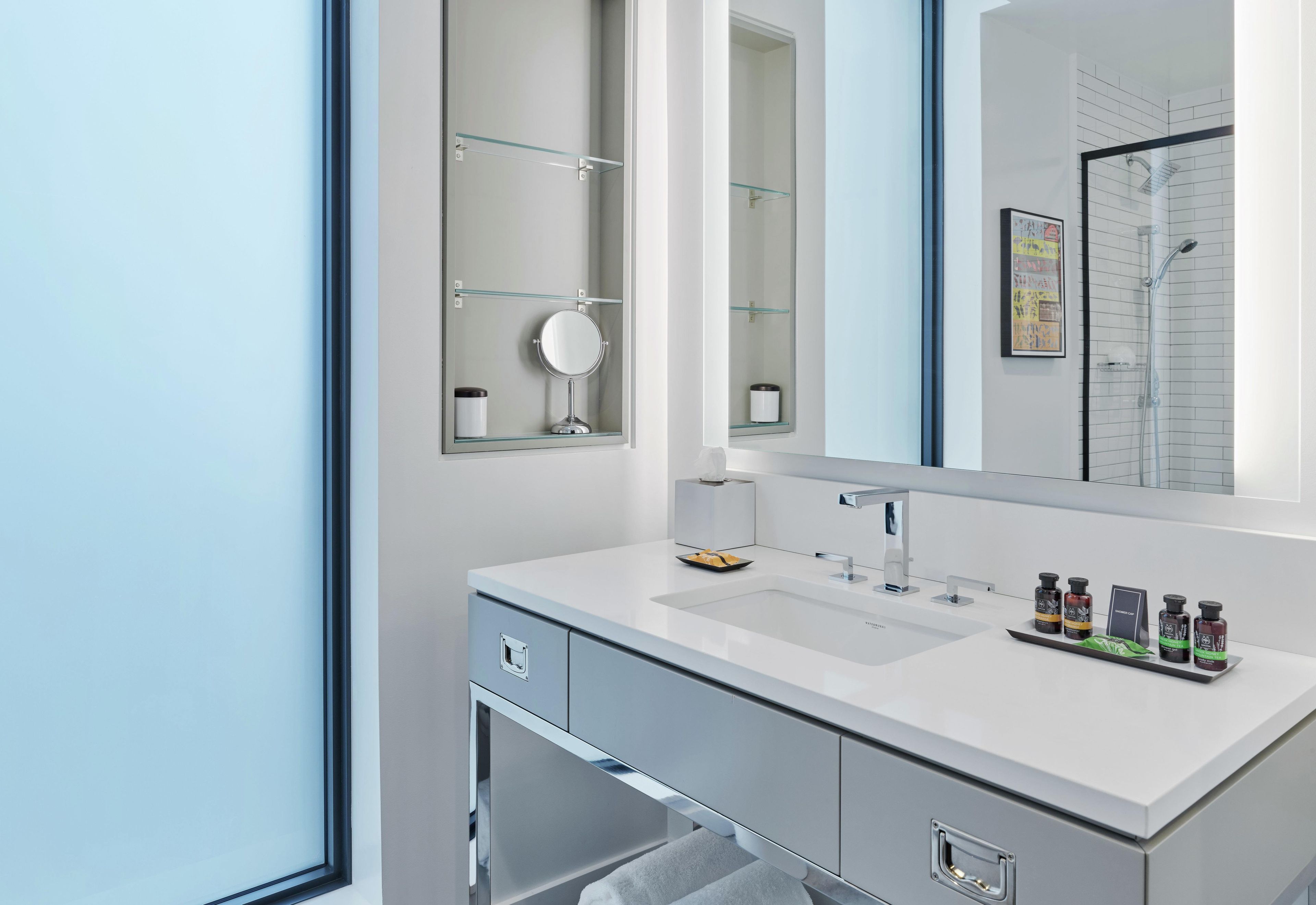 Une salle de bain moderne avec un grand miroir, un lavabo et une douche.