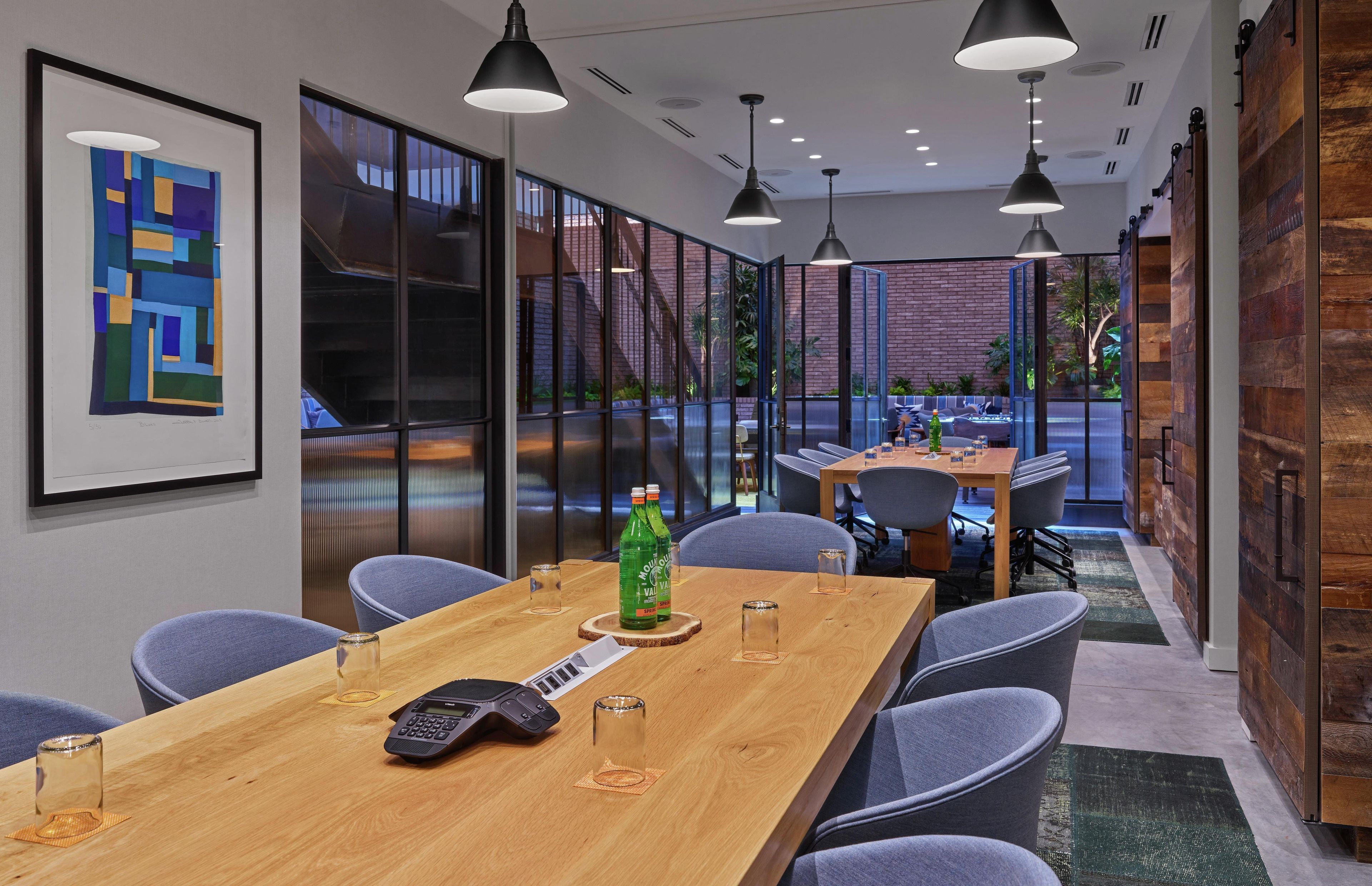 A modern conference room with a long table, chairs, and pendant lighting.