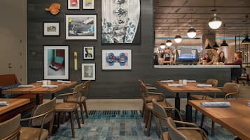 Una cafeteria moderna amb taules i caires de fusta, una barra de cafè i obra d'art a les parets.