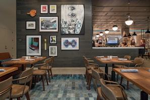 A modern cafe with wooden tables and chairs, a coffee bar, and artwork on the walls. - Canopy by Hilton Portland Pearl District (Portland)