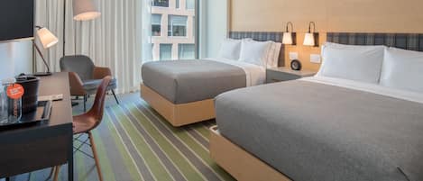 A hotel room with two beds, a desk, a chair, and a large window with curtains.