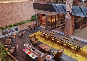 A spacious indoor area with a long dining table, multiple seating arrangements, and a staircase leading to an upper level. - Canopy by Hilton Portland Pearl District (Portland)