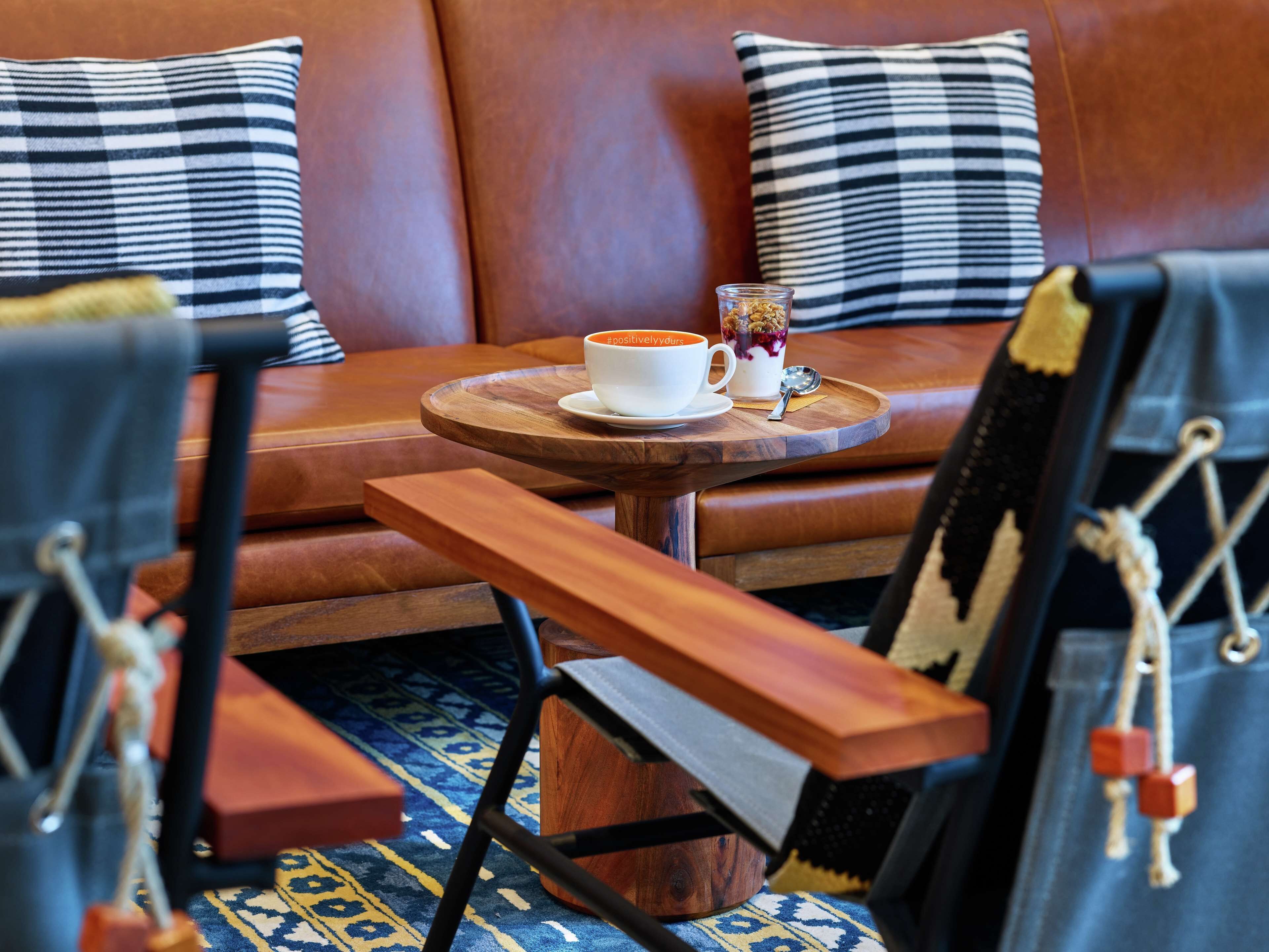 Un coin salon confortable avec une table en bois, deux tasses blanches et une cuillère posées sur un plateau.