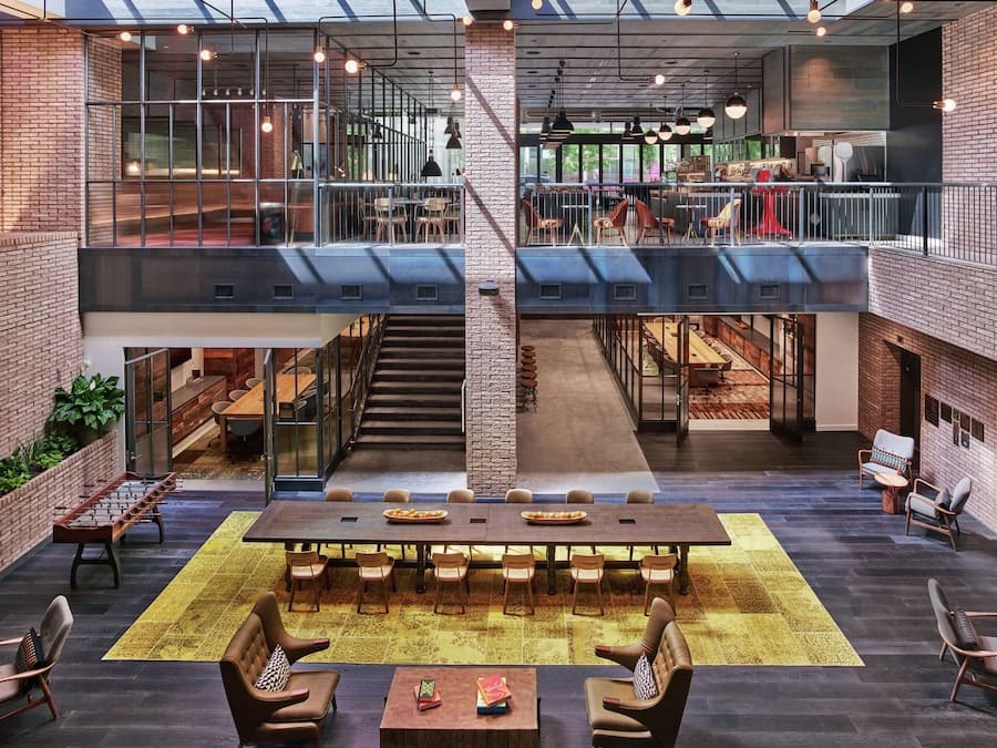 Un espacio interior amplio con una escalera central, varias disposiciones de asientos y vistas al área exterior.