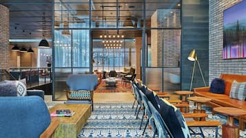Un interior moderno con una zona de estar, una escalera y vistas a través de un muro de cristal.