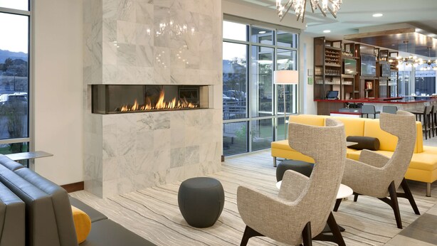 A modern living room with a fireplace, seating area, and a view of the city. - Hilton Garden Inn Lehi (Lehi)