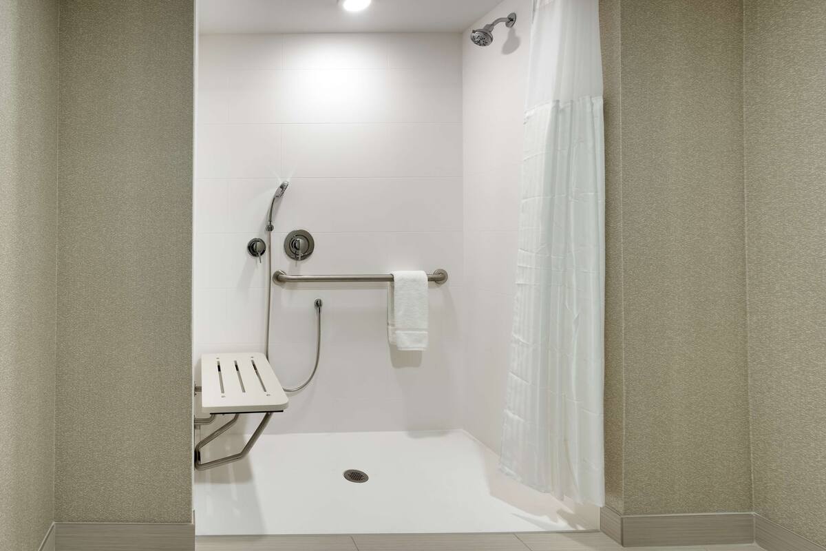 A small, enclosed shower area with a bench, a towel rack, and a showerhead.