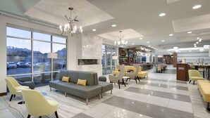 A hotel lobby with a large seating area, a bar, and a view of the parking lot. - Hilton Garden Inn Lehi (Lehi)