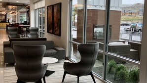 A modern interior with a seating area, large windows, and a view of the outside. - Hilton Garden Inn Lehi (Lehi)